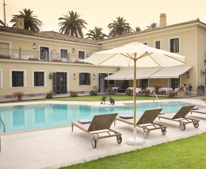 Foto de la piscina al aire libre del hotel con solarium y jardines.