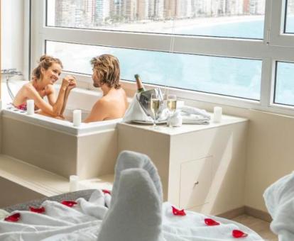 Pareja disfrutando del jacuzzi privado de una de las suites con vistas al mar del hotel.