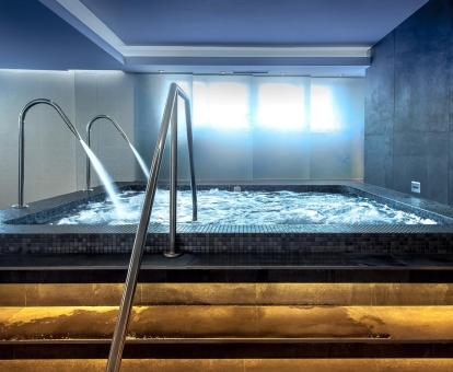 Foto de la piscina cubierta con elementos de hidroterapia del spa del hotel.