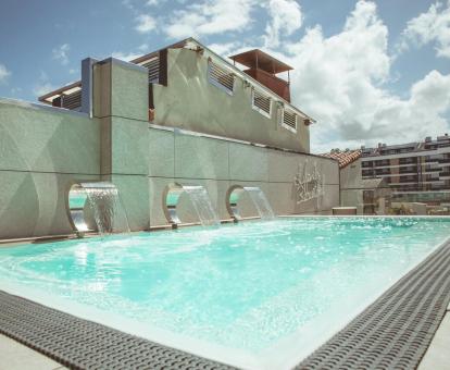 Foto de la piscina al aire libre con chorros de efecto cascada.